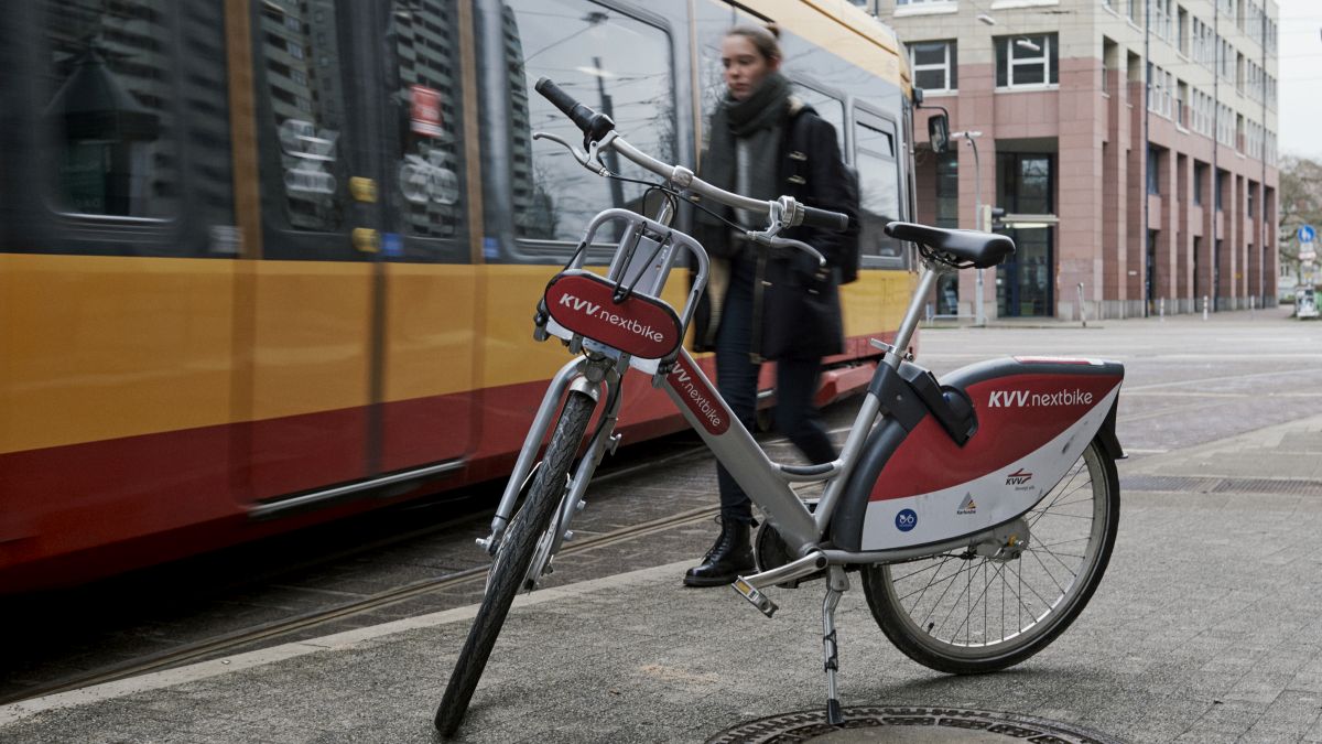 Ein geparktes Fahrrad vor einer vorbeifahrenden Straßenbahn.